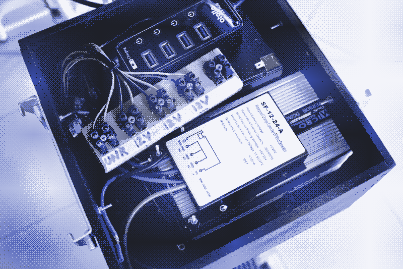 Image: Inside the box: the inverter, the wind charge controller, the lead-acid battery.