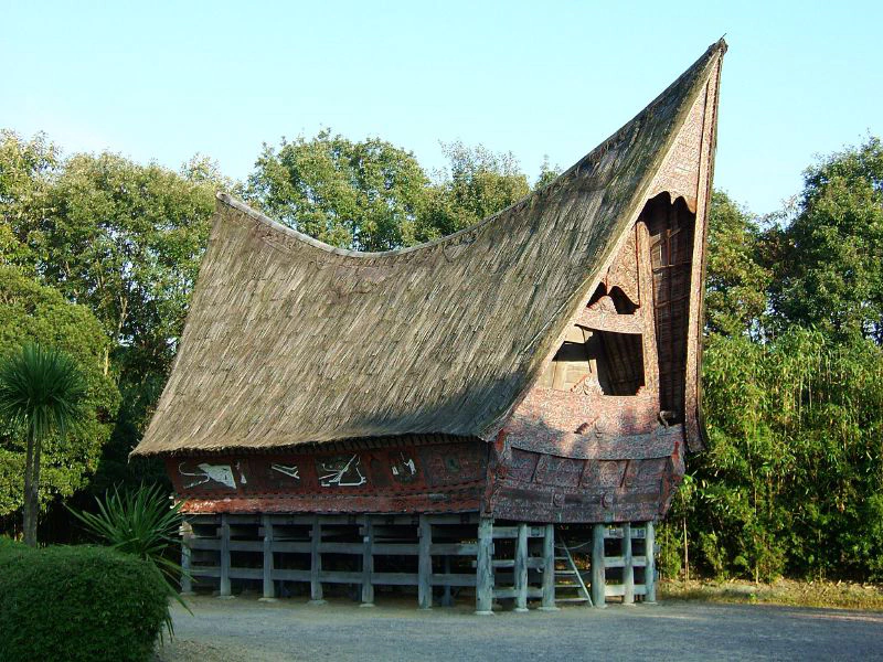 Image: A traditional Batak house in Indonesia, designed to maximize passive cooling and natural ventilation in a warm and humid climate. The thatched roof insulates against solar heat gains, while the high ceiling and the building’s orientation to the prevailing wind direction facilitate the removal of hot air. Photo credit: Mr. Wabu (CC BY-SA 2.0).