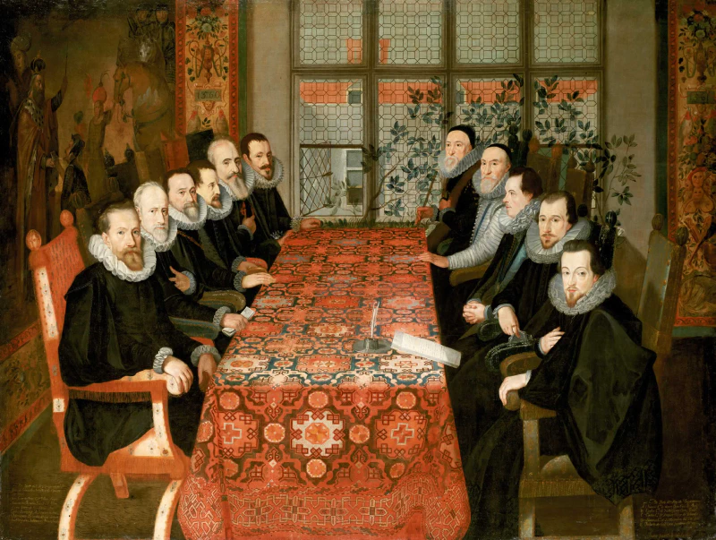 Image: “The Somerset House Conference”. Spanish delegation on the left, English delegation on the right, a table carpet in the middle. A painting by Juan Pantoja de la Cruz, 1604. Image in the public domain.