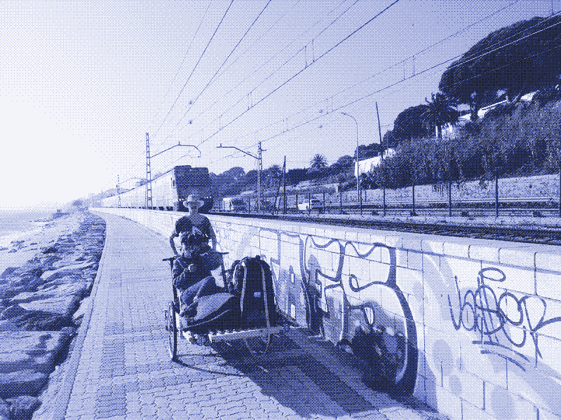 Afbeelding: Kozimo rijdt met de handkar langs de kust. Linda Osusky filmt terwijl ze uitrust op het zitje. Foto door Kris De Decker.